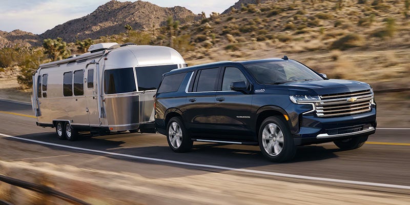 Black 2021 Chevy Suburban hauling airstream camper in desert