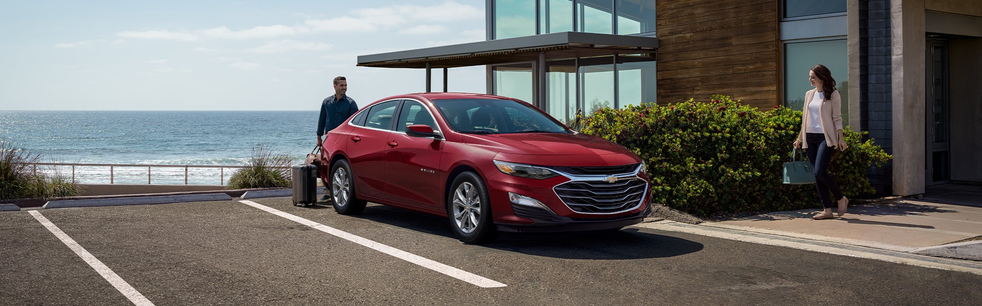 Couple packing red Chevy Malibu at beach house