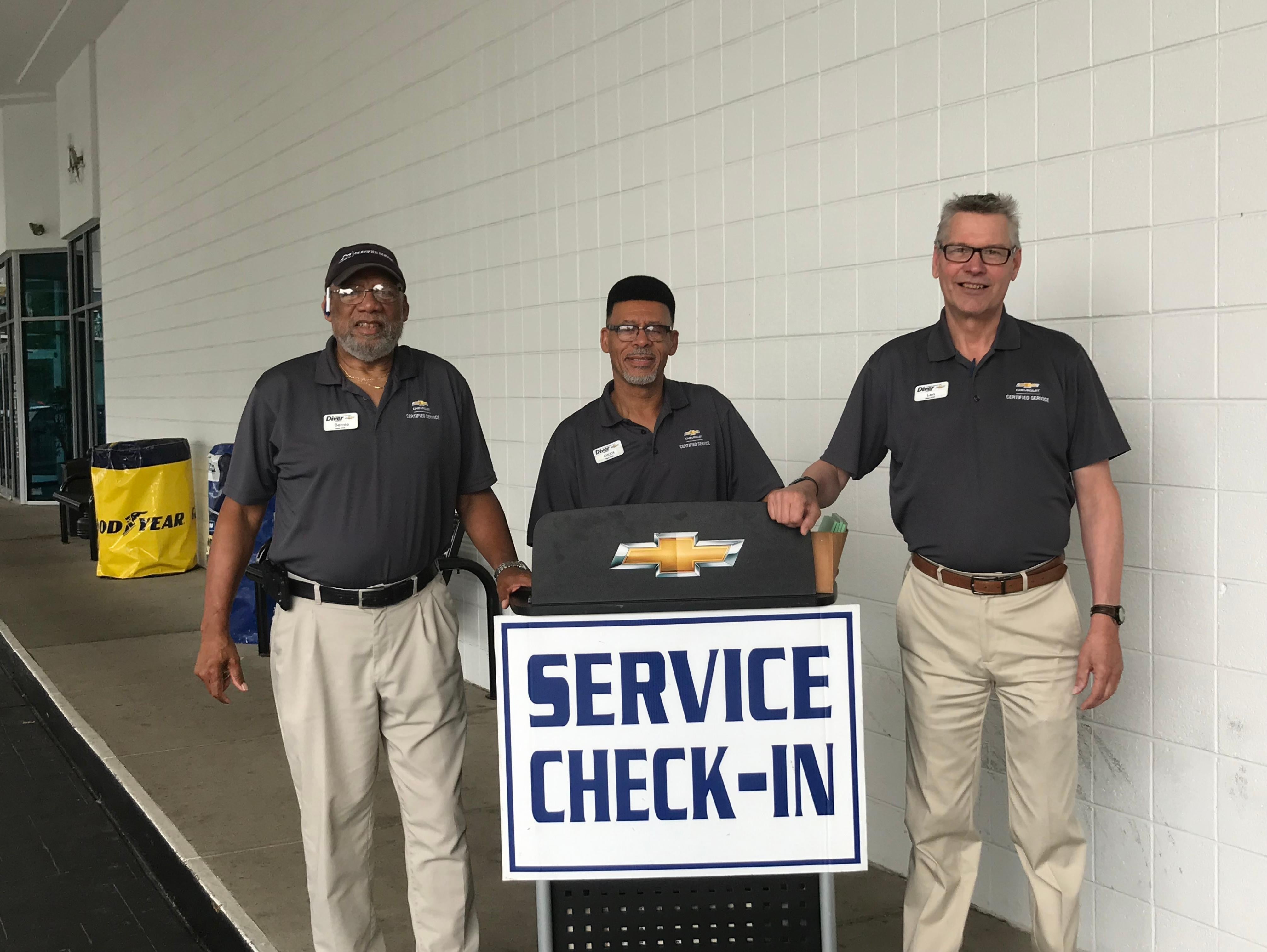 Three men standing with a service check-in board.