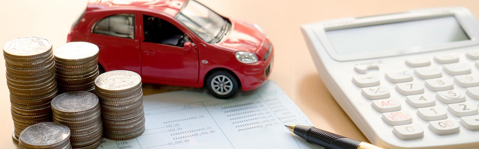 Coins stacked up next to a calculator and a toy car